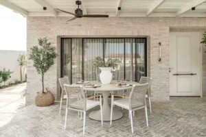 פינת אוכל לחצר מעוצבת עם שולחן עגול וכיסאות חוץ בעיצוב מודרני תחת פרגולה